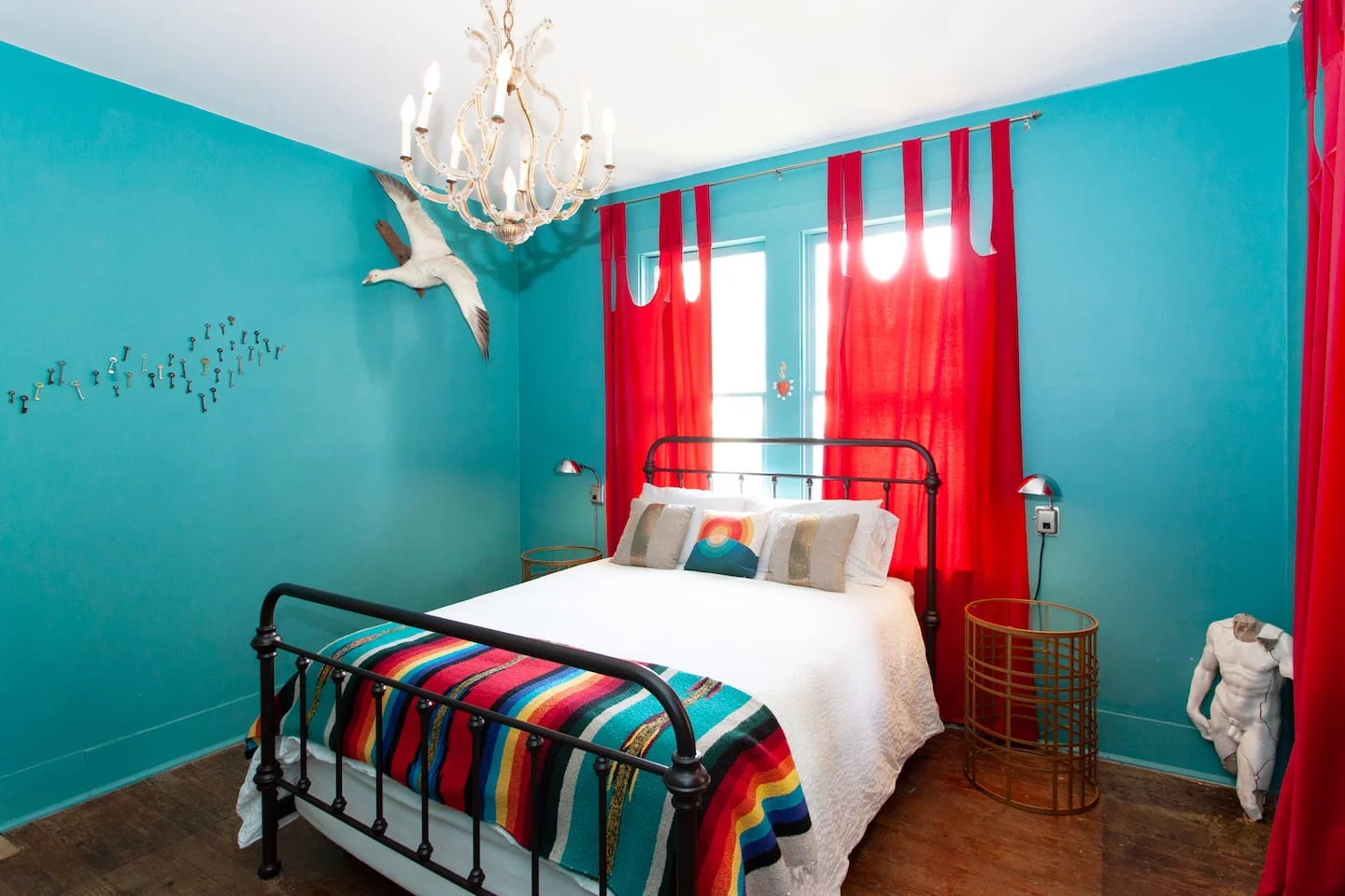 Turquoise bedroom with red curtains and a striped blanket — 2nd St, Austin, Texas