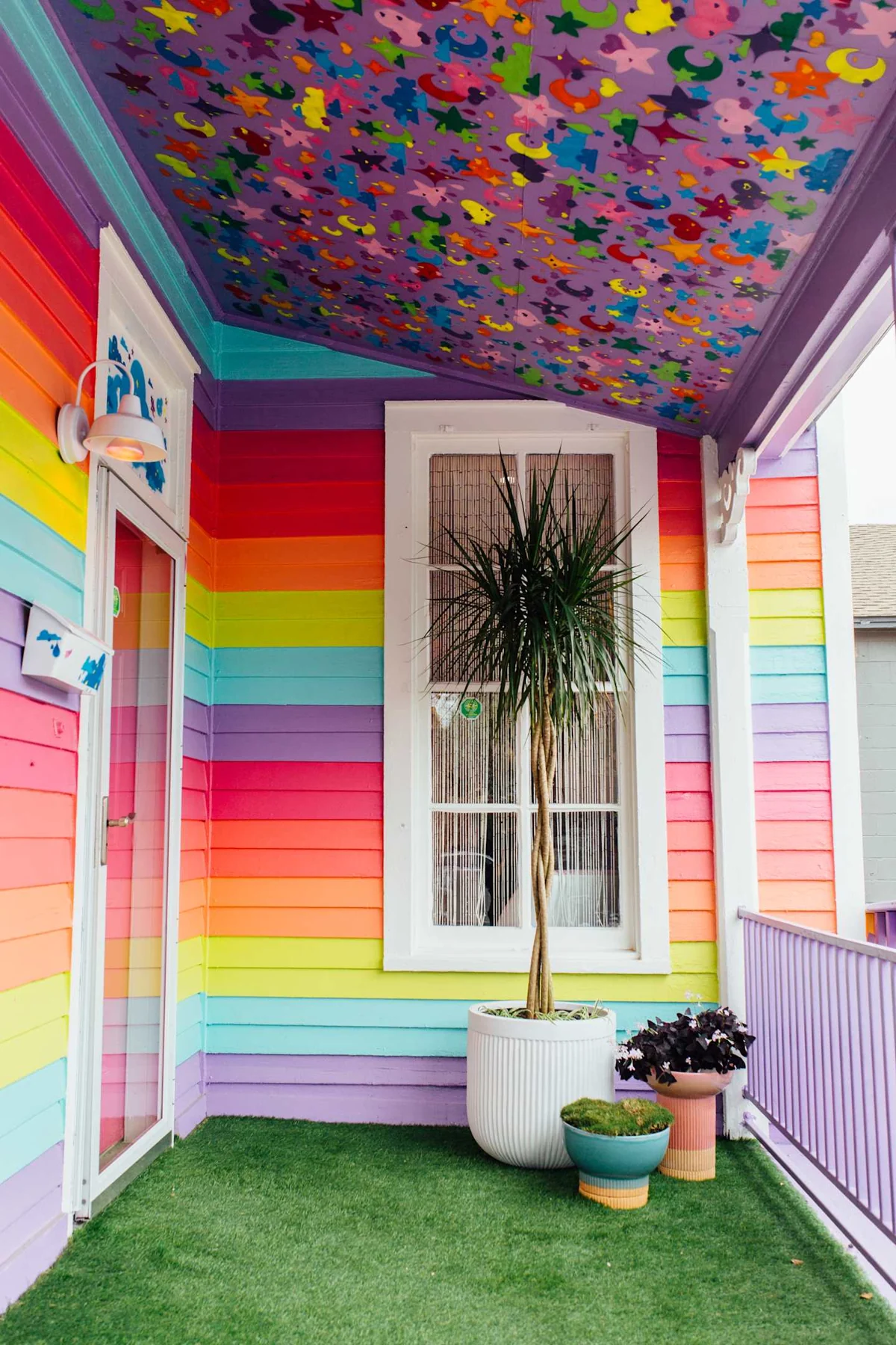 Rainbow-striped entrance with a floral ceiling and green porch floor — Cute Nail Studio, East Austin, Texas