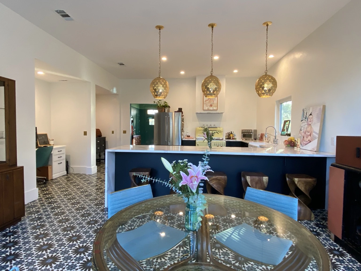 Kitchen and dining area with gold pendant lights, blue seating and patterned tile