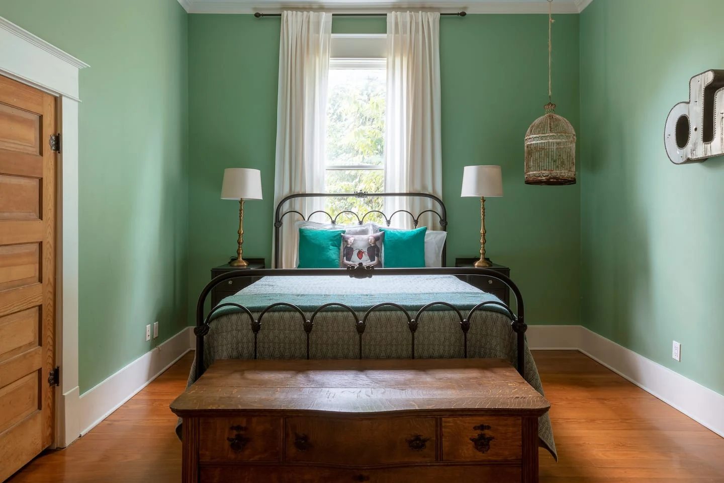 Green bedroom with an iron bed, wood chest and pendant light — Navasota, Austin, Texas