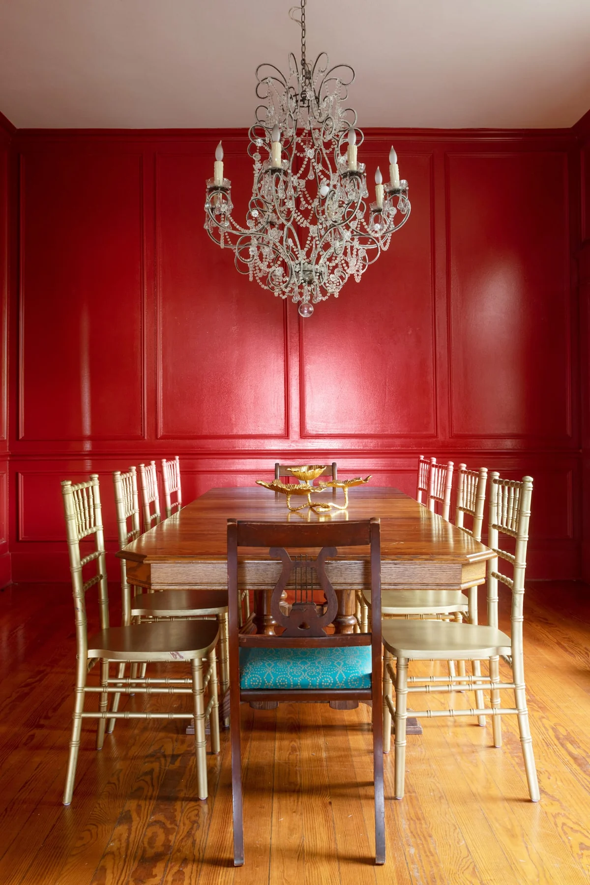 Red dining room with a crystal chandelier, wood table and gold chairs — Navasota, Austin, Texas