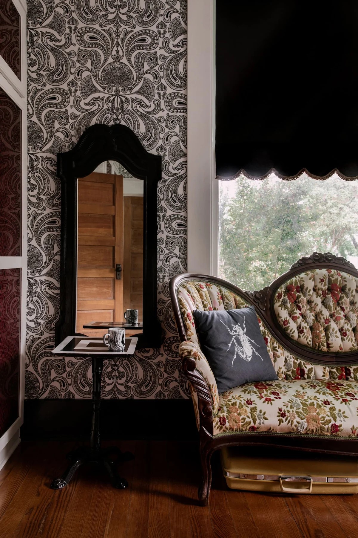 Vintage floral sofa and dark-framed mirror against patterned wallpaper — Navasota, Austin, Texas
