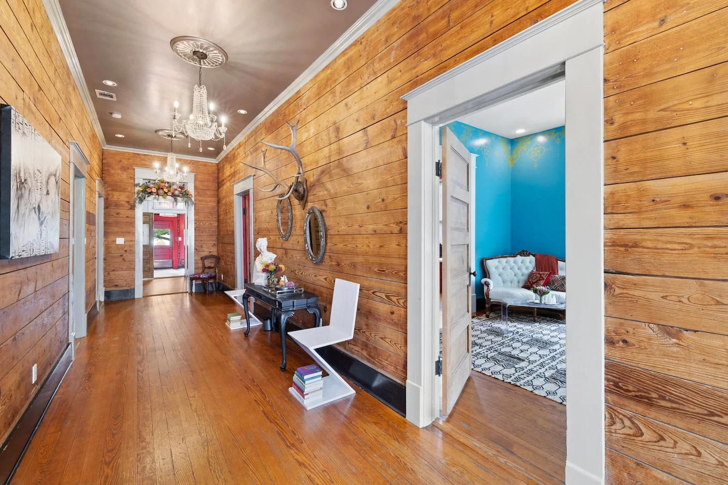 Wood-paneled hallway with a chandelier and blue doorway — Navasota, Austin