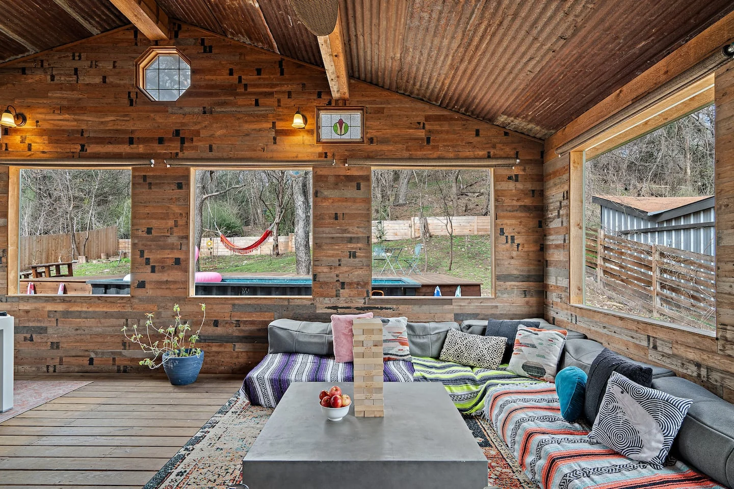 Wood-paneled sunroom with a long sofa and colorful cushions — Oak Springs, Austin, Texas