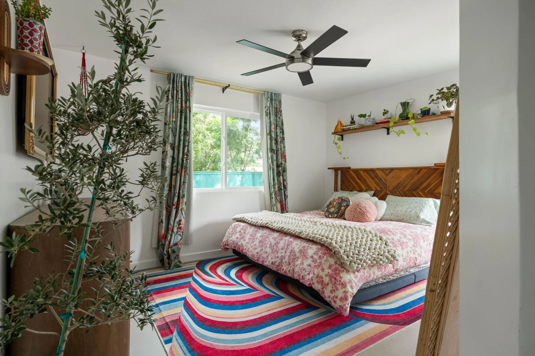 Bedroom with a timber headboard, plants and a wavy striped rug — Woodhue, South Austin, Texas