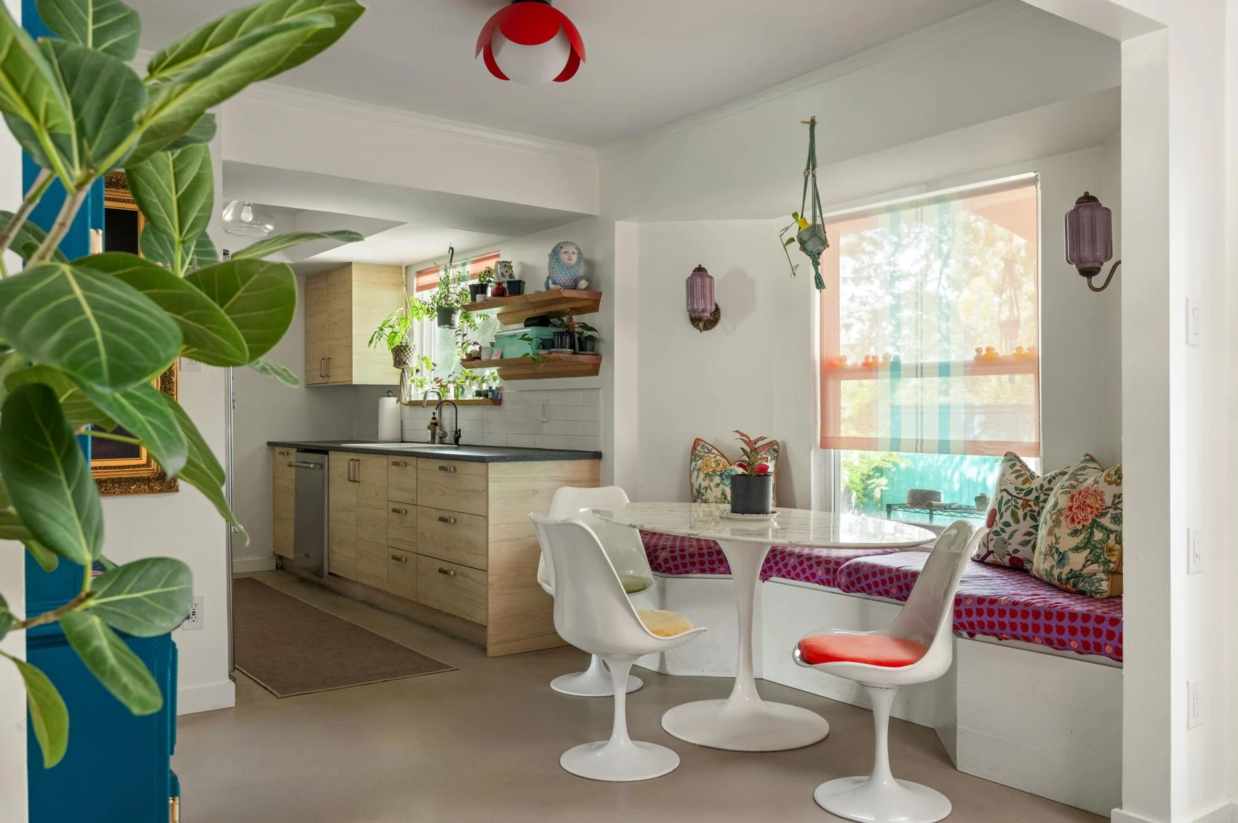 Dining nook with white tulip chairs, plants and bright cushions — Woodhue, South Austin, Texas