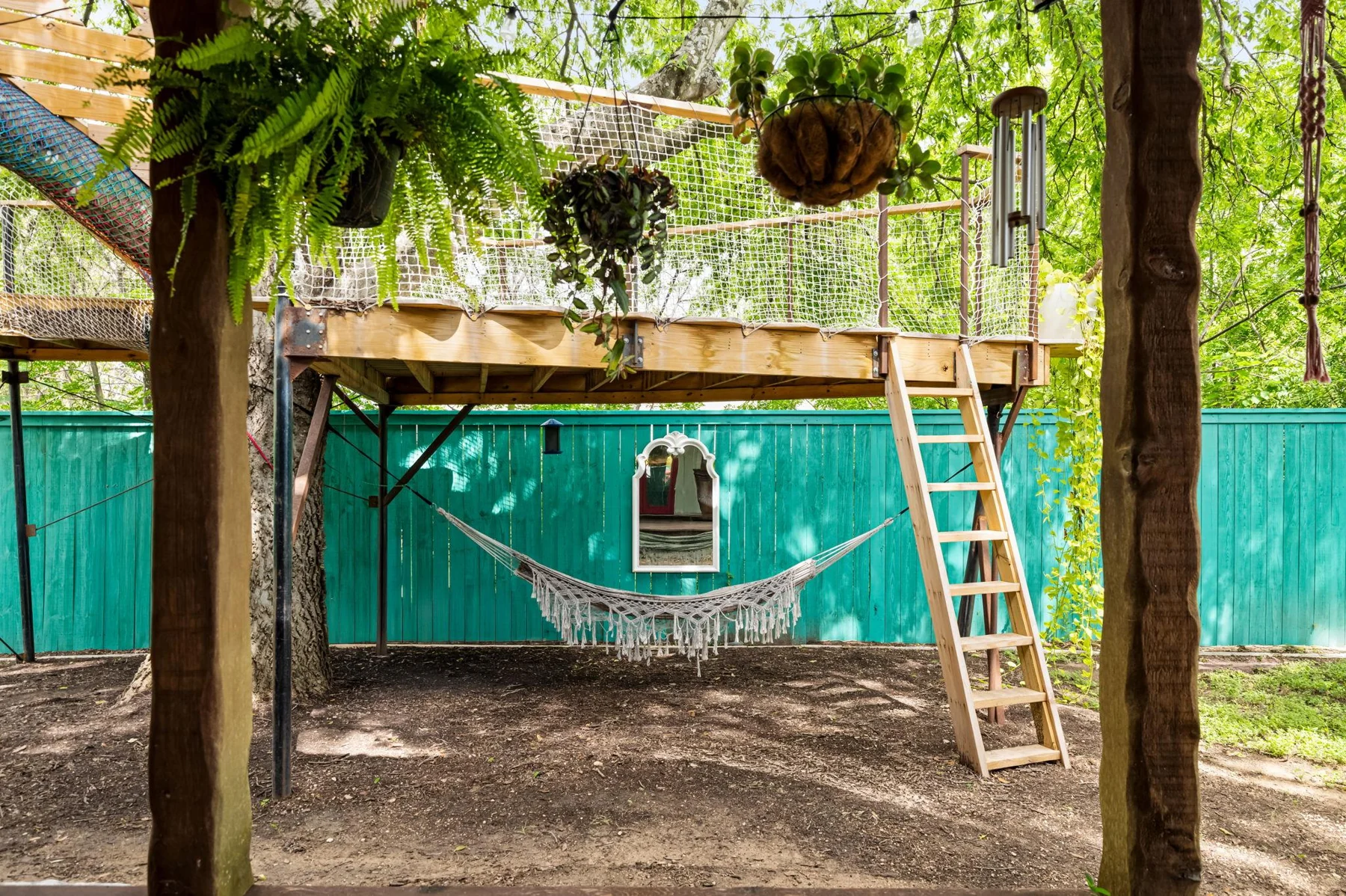 Leafy backyard with a green treehouse and wooden ladder — Woodhue, South Austin, Texas