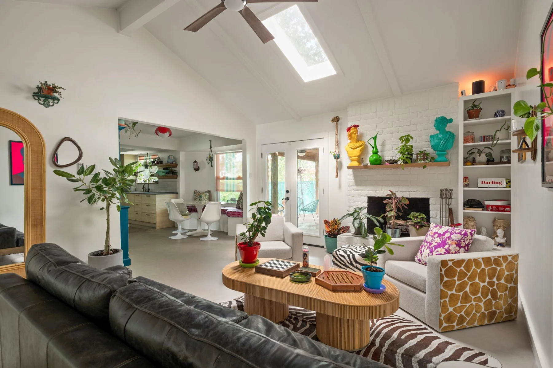 Light-filled living room with plants, a dark sofa and colorful artwork — Woodhue, South Austin, Texas